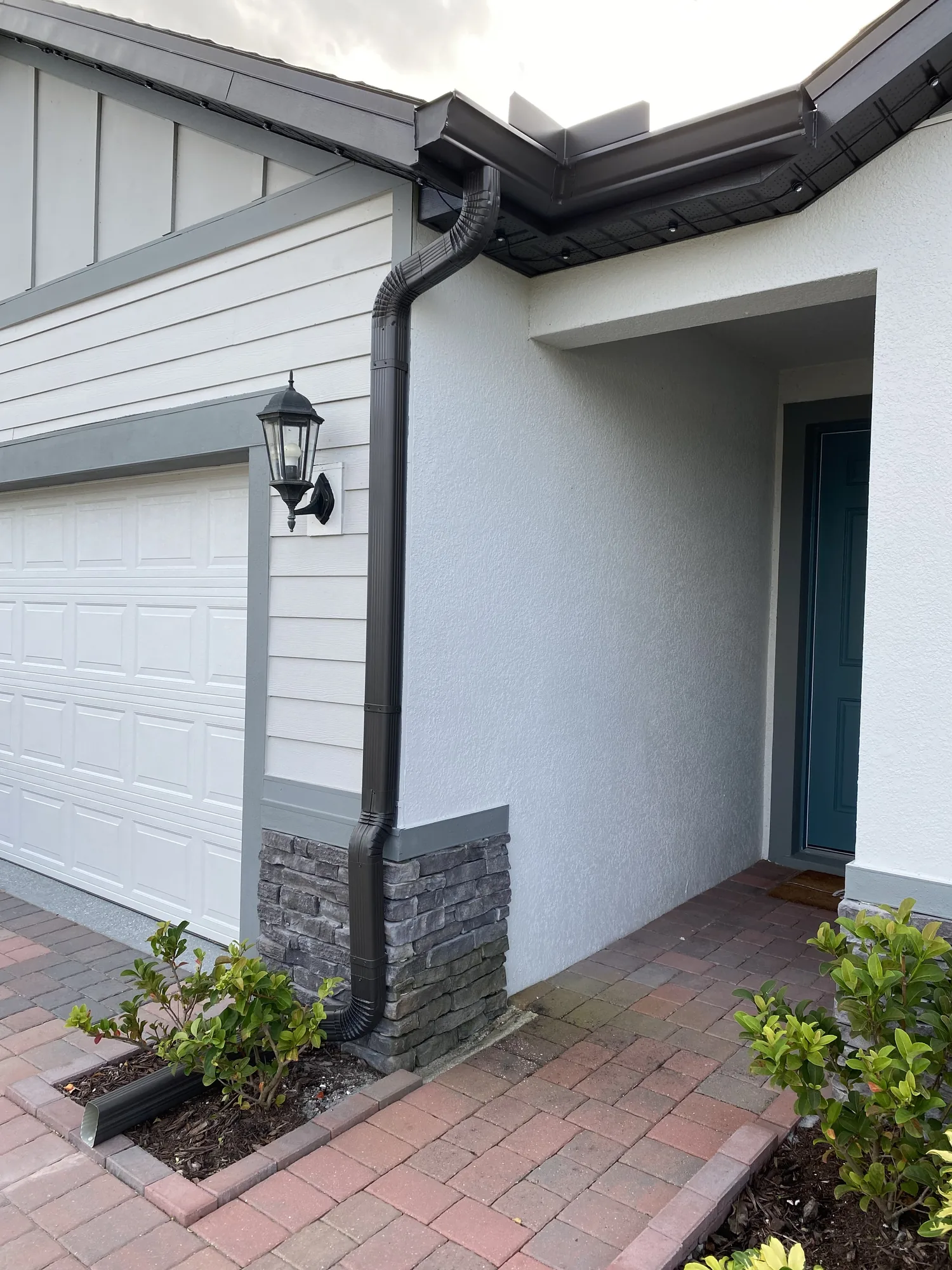 Dark gutter and custom downspout installed at a residential entry